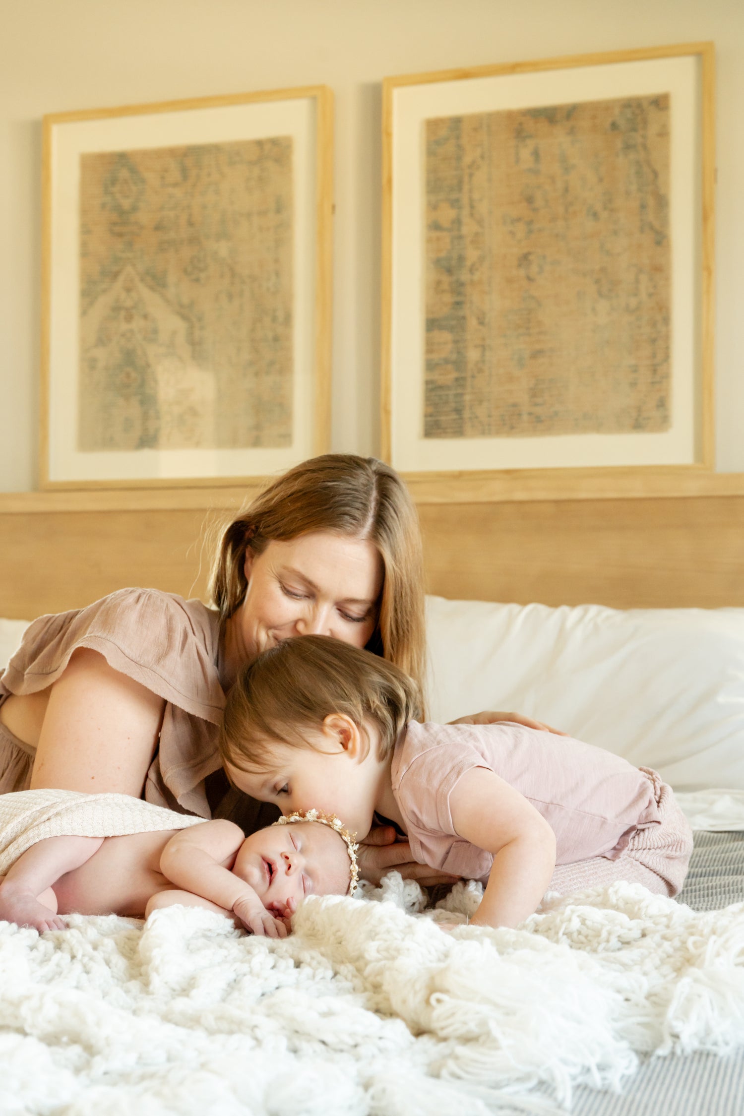 Mother kissing her toddler and the toddler kissing a newborn